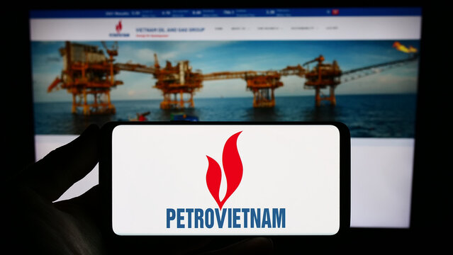 Stuttgart, Germany - 07-27-2023: Person holding smartphone with logo of oil and gas company PetroVietnam (PVN) on screen in front of website. Focus on phone display.