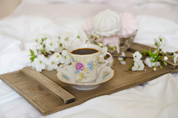 Obraz na płótnie Canvas cup of coffee with blossom flowers on white bed
