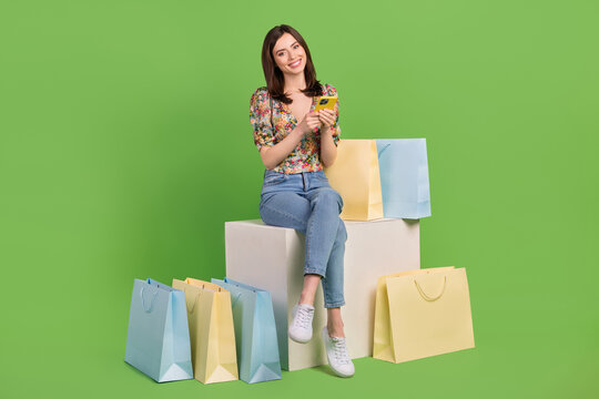 Full length body photo of young blogging girl hold her phone with much bargains shopaholic order more isolated on green color background