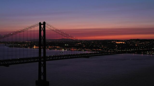Ponte 25 de Abril Suspension Bridge Connecting Lisbon to Almada. Evening Twilight, Blue Hour. Portugal. Aerial View. Orbiting