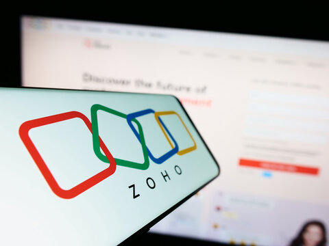 Stuttgart, Germany - 07-28-2023: Mobile phone with logo of Indian technology company Zoho Corporation on screen in front of website. Focus on center-left of phone display.