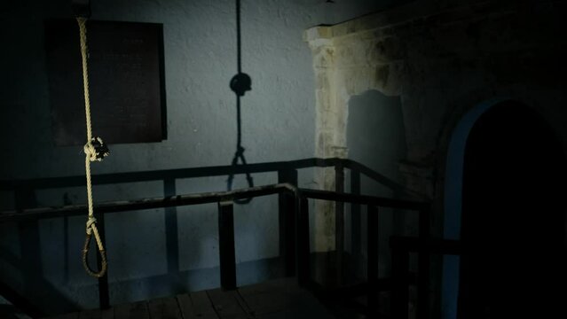 The camera is focusing into an authentic hanging chamber. the shadow of the rope on the bare wall, enhances the creepy feeling of the place. a 4K video clip.