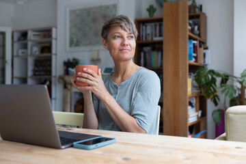 Mid adult female working on personal finances using a laptop and a smartphone 