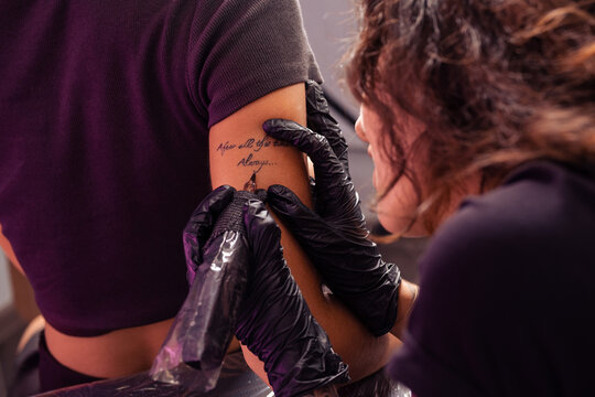 Talented artist crafting personalized lettering tattoo on female arm