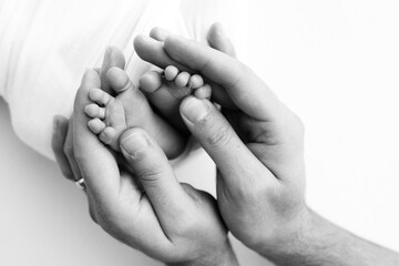 The palms of the father, the mother are holding the foot of the newborn baby on white background.
