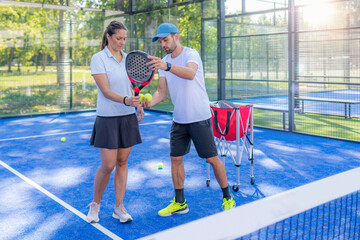 Padel coach and female padel player learning techniques on the court.