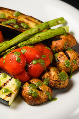 Assorted grilled vegetables with pesto sauce on a white plate.