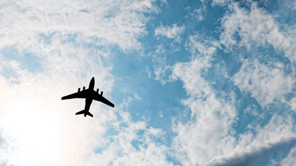 Silhouette of an airplane in a blue cloud sky. Concept. Copyspace.