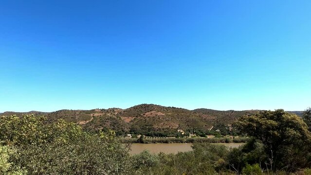 Rio Guadiana high altitude viewpoint in Portugal looking towards Spain across the river in strong winds, sunshine and blue skies