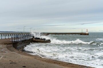 View of waves crashing at the harbour wall in Amble, Northumberland, UK.