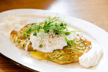 Zucchini fritters, vegetarian zucchini pancakes, served with poached egg and sour cream.