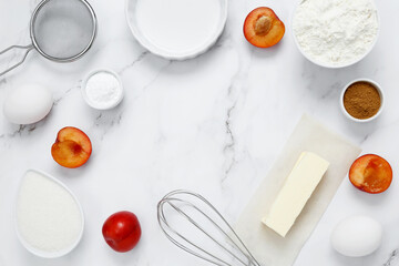 Ingredients for making classic cake pie with plums on white background. Concept homemade food, seasonal pastries. Top view, copy space
