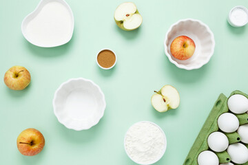 Ingredients for making classic cake pie with apples on green background. Concept homemade food, seasonal pastries. Top view, copy space