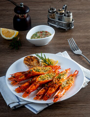 Grilled garlic butter prawns, in a plate on a wooden table