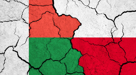 Flags of Madagascar and Poland on cracked surface - politics, relationship concept