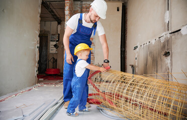 Father and little son working with mesh fiberglass rebar and pipes in apartment under renovation....
