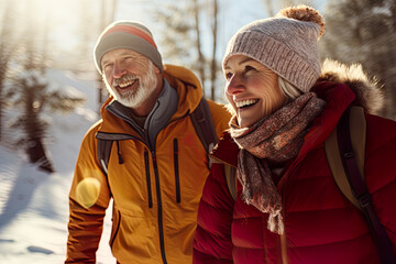 Best agers enjoying a winter walk, snowy forest. Senior couple walking in a forest, snow falling. Happiness of being outdoors and having mobility.