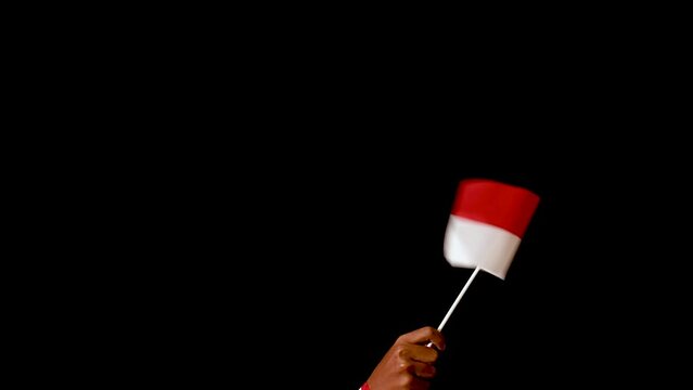 Male hand holding Indonesia flag, waving it and making a circular pattern over the dark background