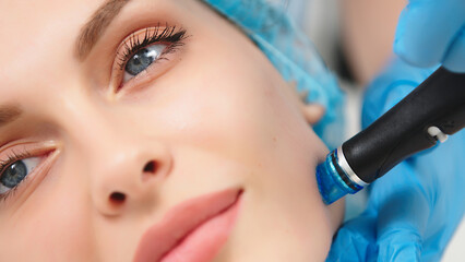Professional qualified beautician standing next to client during hydrafacial procedure. Pleasant...