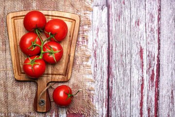 bunch of fresh, ripe tomatoes on a cutting board. View from above. Space for text.