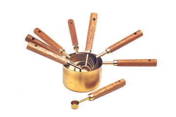 Copper measuring cups/spoons with wooden handle in sets of different sizes on white background.