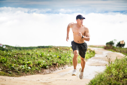Athletic healthy man running in mountain with clouds landscape background. Fitness Asian trail runner male sprinting outdoors. Full length shot. Healthy lifestyle - Powered by Adobe