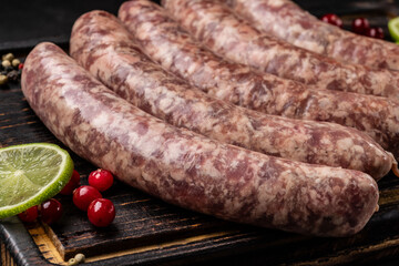 German cuisine. Raw sausages from the sausage on a wooden board, on a black background.