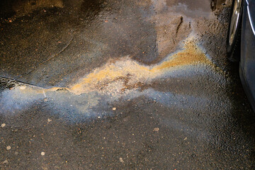 Leakage of oil or gasoline from the car on the asphalt in the parking lot