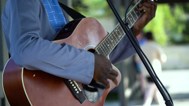 A street musician plays an acoustic guitar for passers-by in the city square