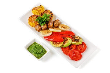 grilled tomatoes, zucchini, mushrooms, corn, onions, peppers and sauce on a white background for a restaurant menu, studio shooting 1