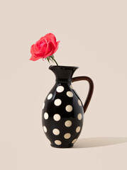 Wild rose in a black vase with polka dots. Minimal aesthetic concept of flower arrangement.