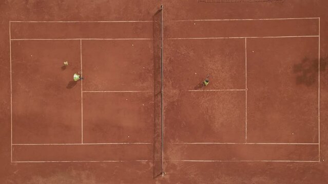 From above: a father teaches his son to play tennis, lovingly passing on his knowledge and experience.