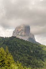 Montagne isolée dans les nuages devant une forêt. Mont aiguille, Vercors