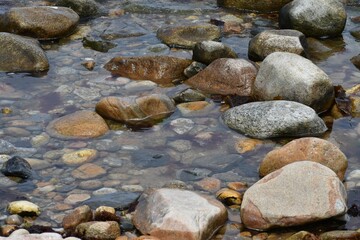 Fototapeta na wymiar Tranquil stream meanders between the scatteredrocks