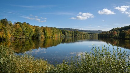 Fototapeta na wymiar Tranquil Henne Lake surrounded by vibrant foliage in Sauerland, Germany