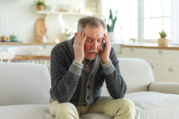 Headache pain. Unhappy middle aged senior man suffering from headache sick rubbing temples at home....
