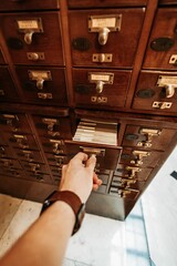 Man opening a vintage wooden cabinet with book note cards