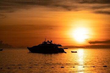 Yacht on the sea silhouetted against a vibrant orange sunset
