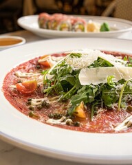 Steaming hot bowl of beef carpaccio topped with ruccula and parmesan slices