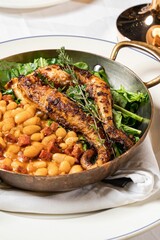 Bowl of juicy grilled octopus with chorizo and beans on the table