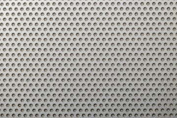 Closeup of the metallic grill texture of the speaker featuring numerous holes