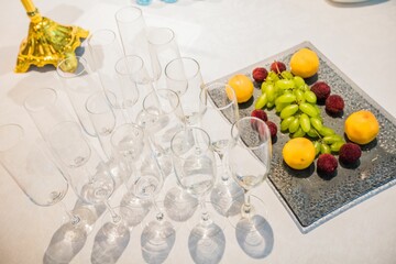 There is a pile of glasses and fruits on the table