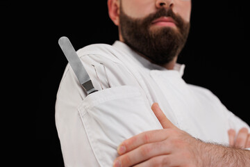 Close-up of a chef with a knife in his pocket on a black background.