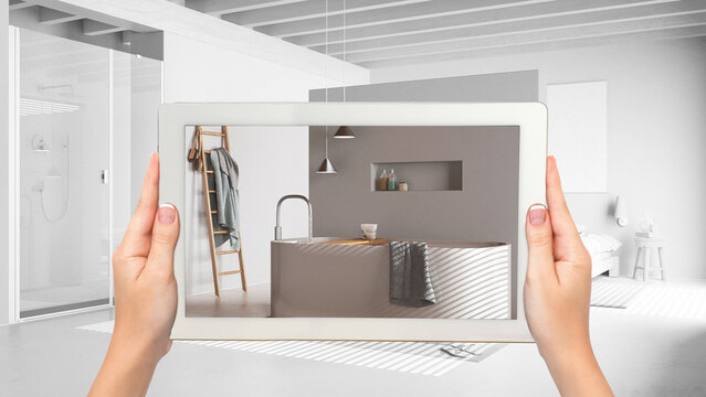 Augmented reality concept. Hand holding tablet with AR application used to simulate furniture and design products in total white unfinished background, minimal bathroom and bedroom