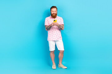 Full length portrait of positive eccentric person hold use smart phone chatting isolated on blue color background