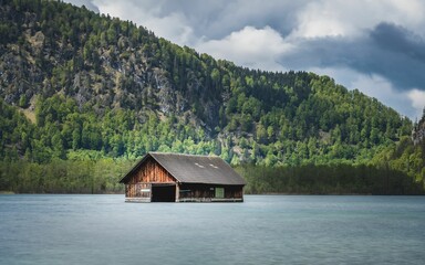 Scenic view of a wooden house on a lake in green mountains