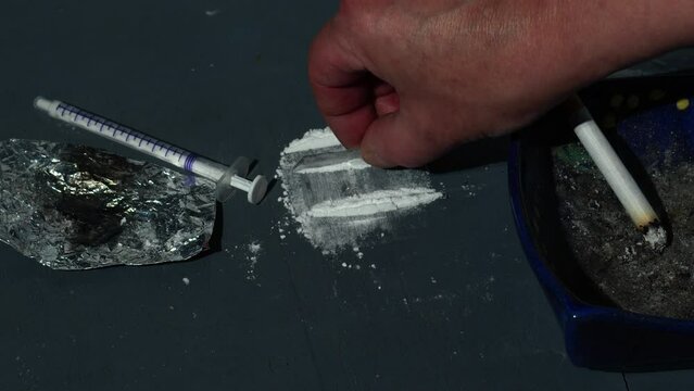 Drug addict preparing lines of cocaine 