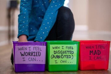 Child sits on the ground in front of bins for kid therapy session