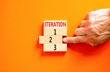 Time to iteration 2 symbol. Concept word Iteration 1 2 3 on wooden block. Businessman hand. Beautiful orange table orange background. Business planning and time to iteration 2 concept. Copy space.