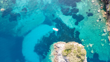 Top picture of  with a turquoise blue lagoon at Mediterranean, some boats and a lot of green trees, and a lake on the top of the picture. Aerial view of the famous  island and Blue lagoon.